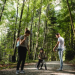 Mutter Vater und Kind im Wald diskutieren über den Weg, Kind ist auf dem Laufrad